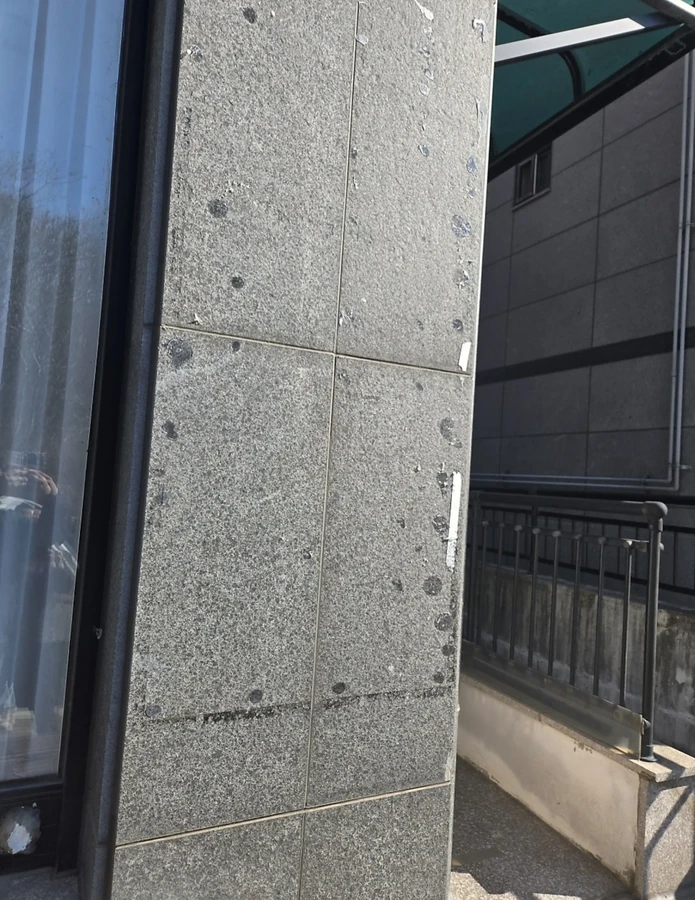 건물 모서리 석재 기둥에 스티커 자국과 얼룩이 남은 제거 전 현장